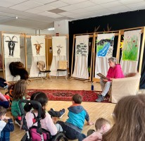 Frau Brill in einem Sessel vor den Bildern zur Geschichte "Drei Ziegen"